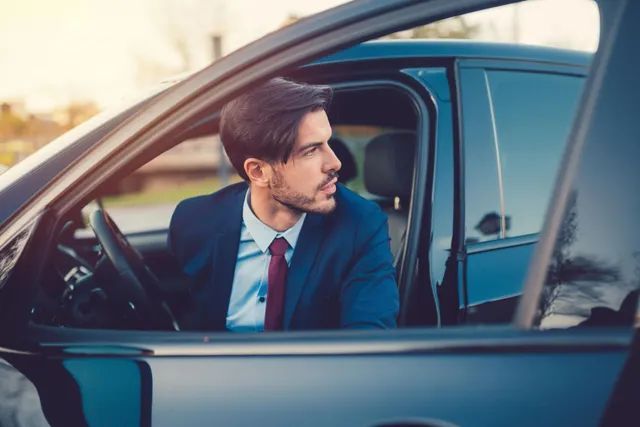 A man in a suit and tie is sitting in a car.