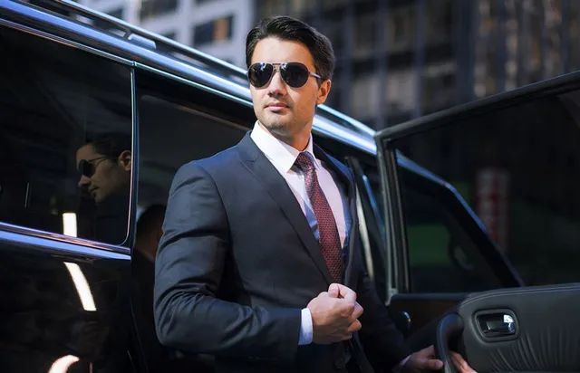 A man in a suit and tie is getting out of a car.