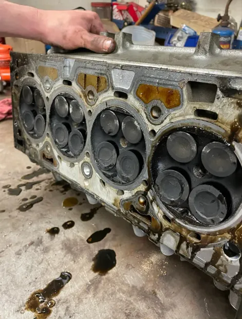 Engine cylinder head with valves, covered in oil and soot. | American Fleet & Auto Service