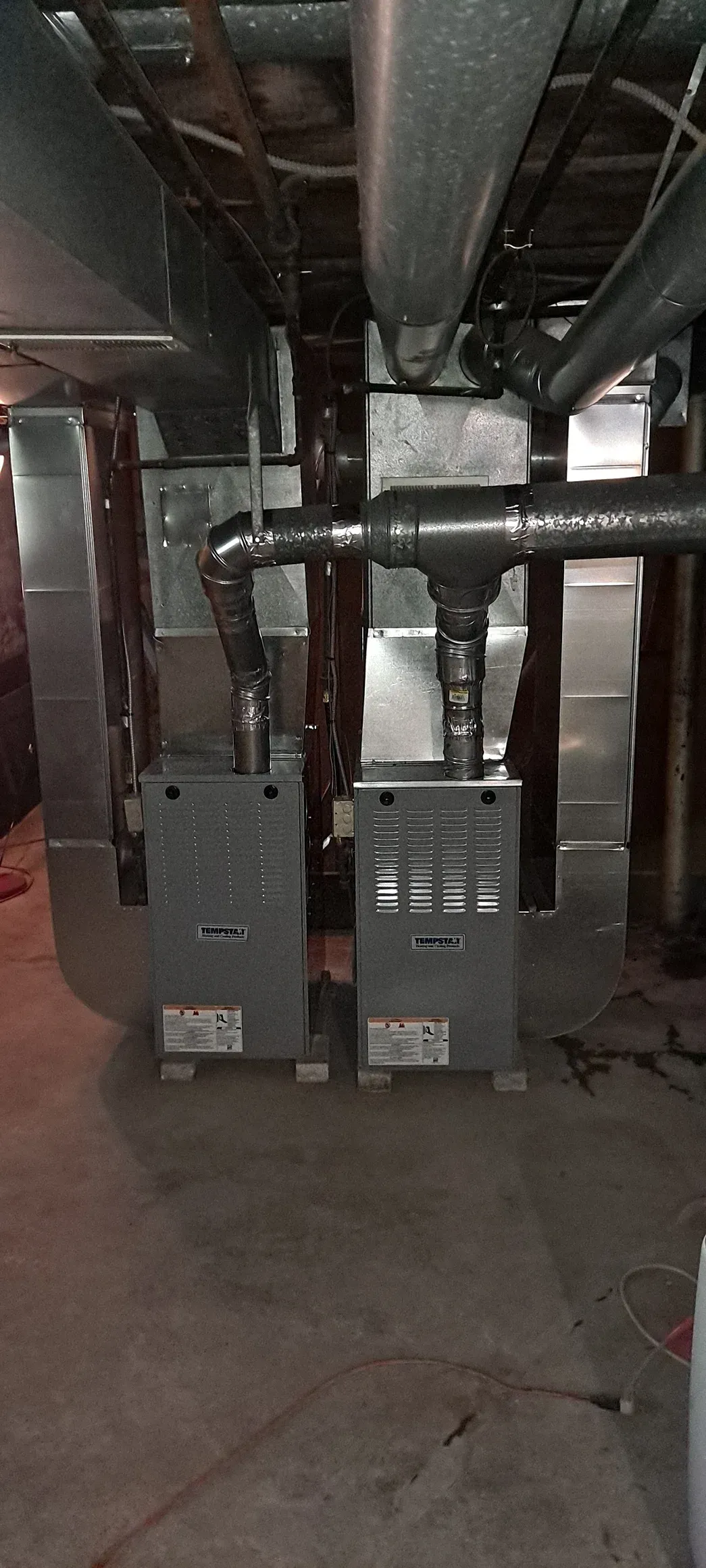 Dim basement utility room with exposed pipes and electrical boxes on the wall
