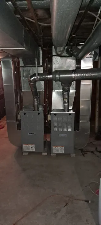 Dim basement utility room with exposed pipes and electrical boxes on the wall
