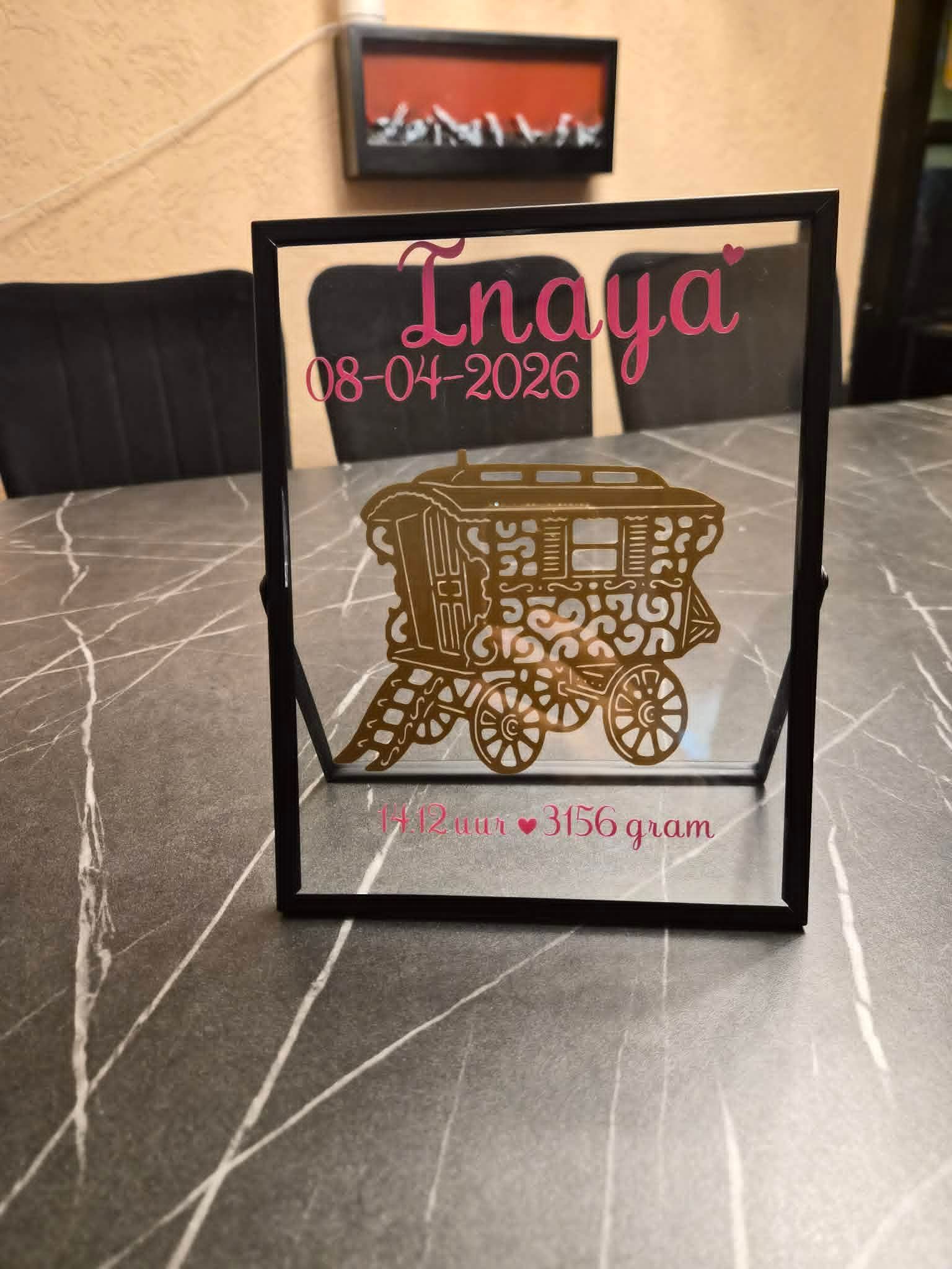 Decoratieve geschenkdoos met blauwe strik en transparante folie op een eettafel naast een boeket rode rozen.