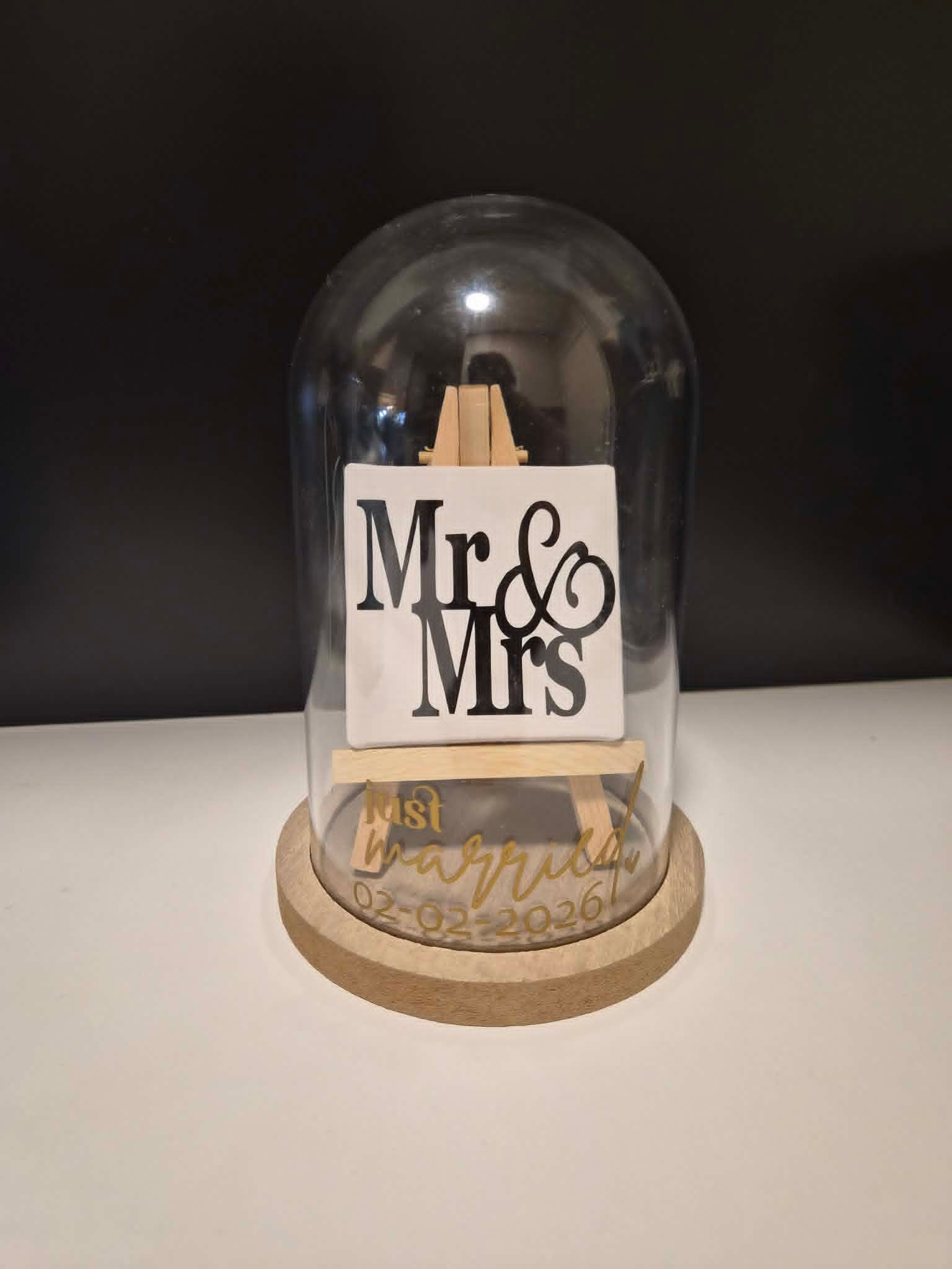 Decoratieve trouwdecoratie onder een glazen koepel met de tekst 