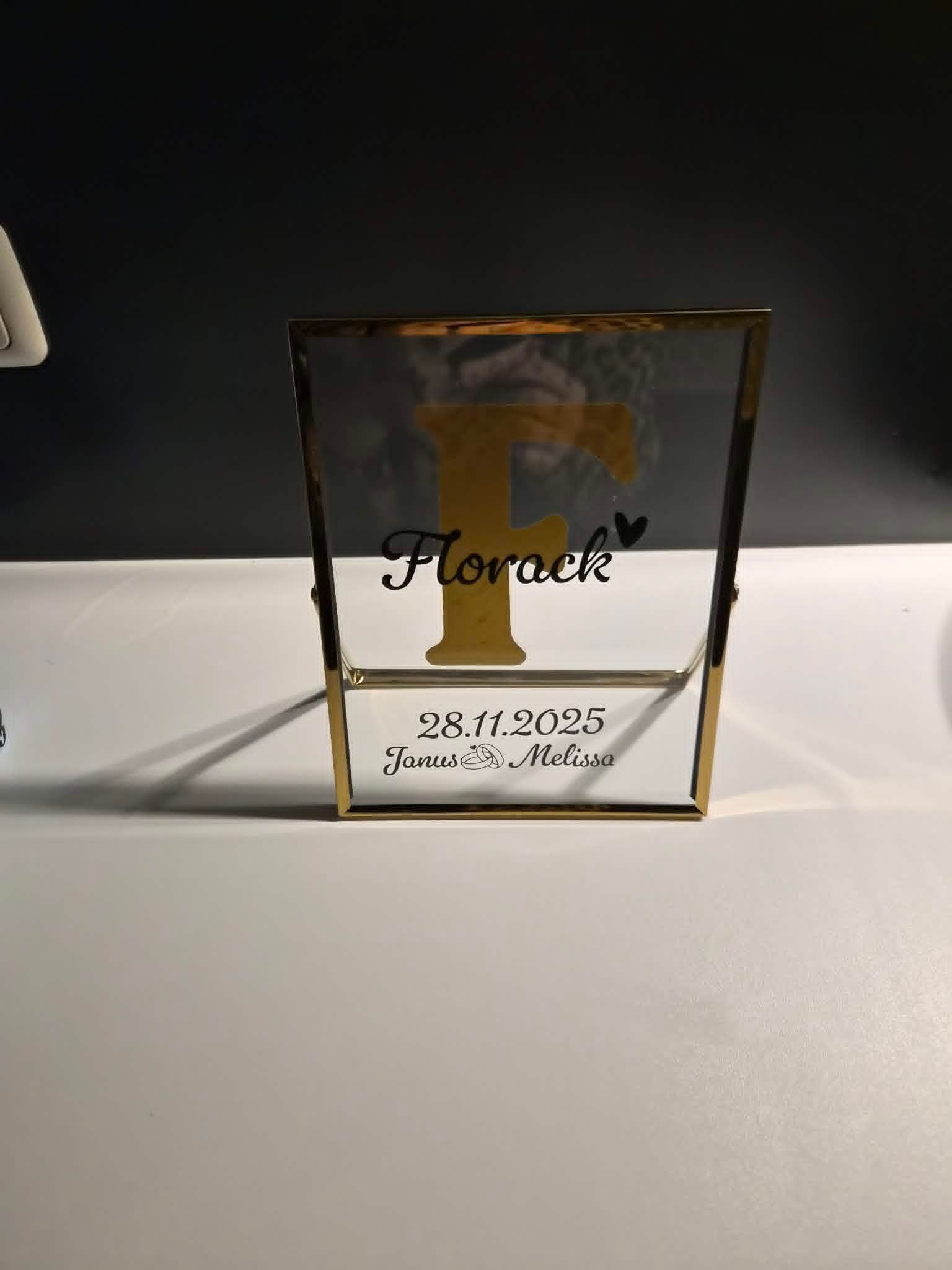 Kleine verpakking met bloemenpatroon en gouden rand op een witte ondergrond tegen een donkere achtergrond.