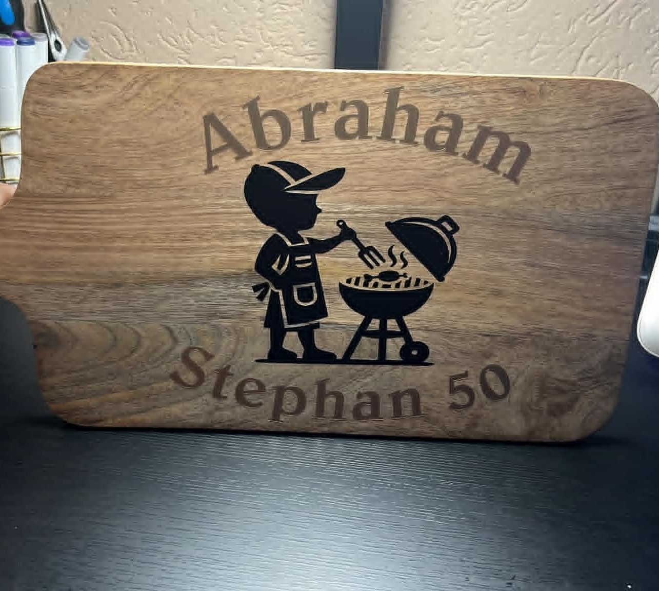 Houten plaquette met een silhouet van een barbecue en de namen 