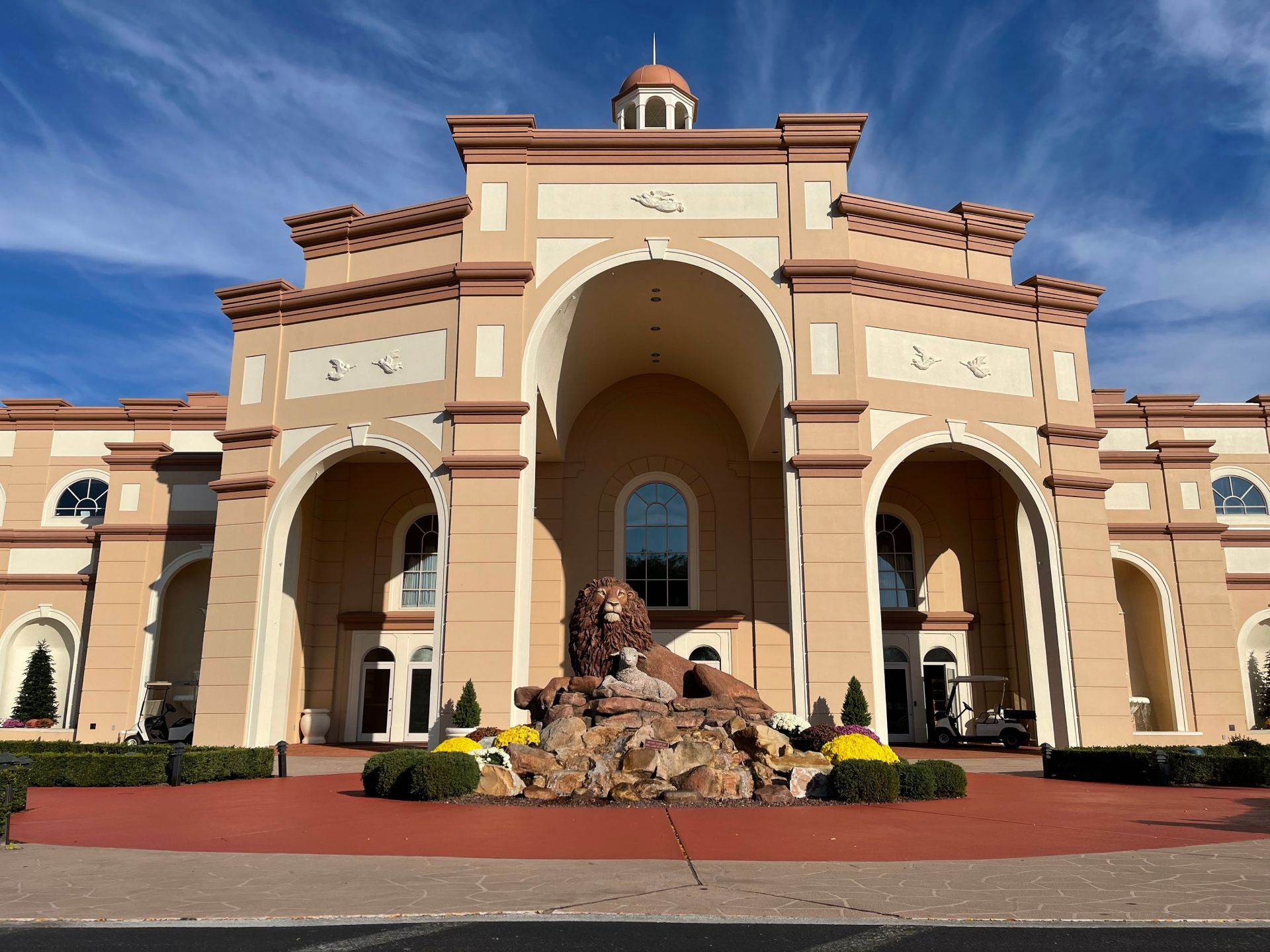 Grand Mediterranean-style building with arched entrance and fountain under a blue sky