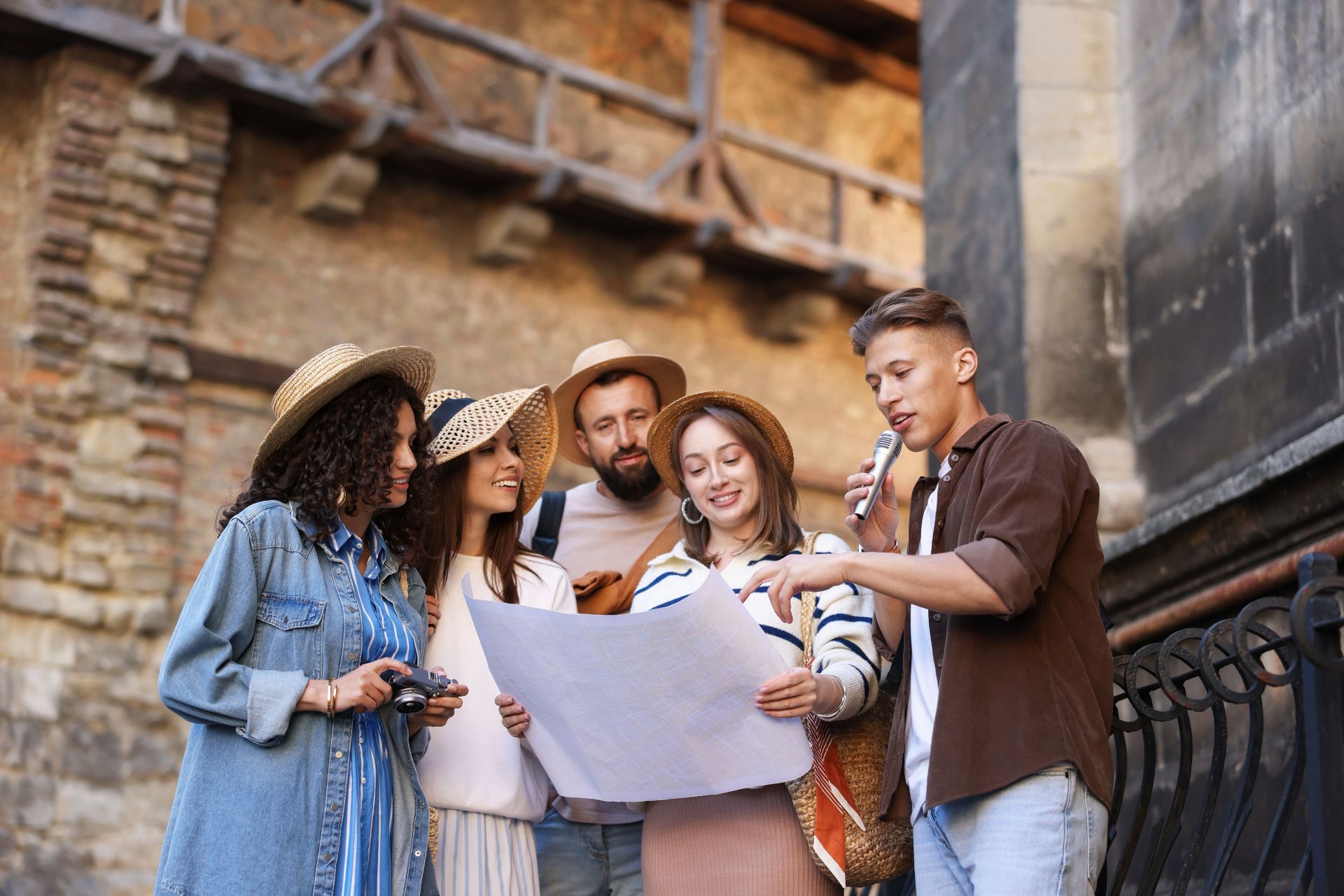 Four friends studying a large map outdoors on a historic street, pointing and talking together.