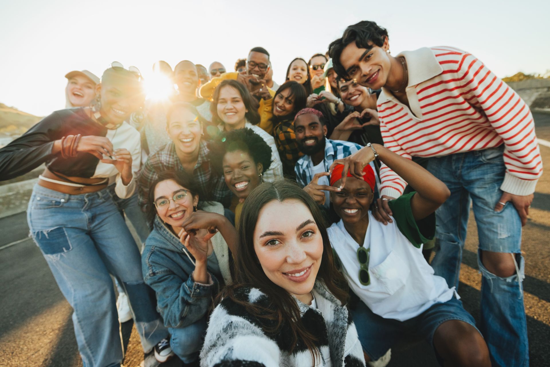 Group of friends smiling for a selfie outdoors at sunset