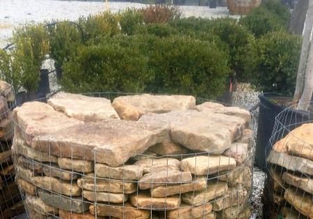 Stacked stone gabions beside a green shrub in an outdoor landscape garden.