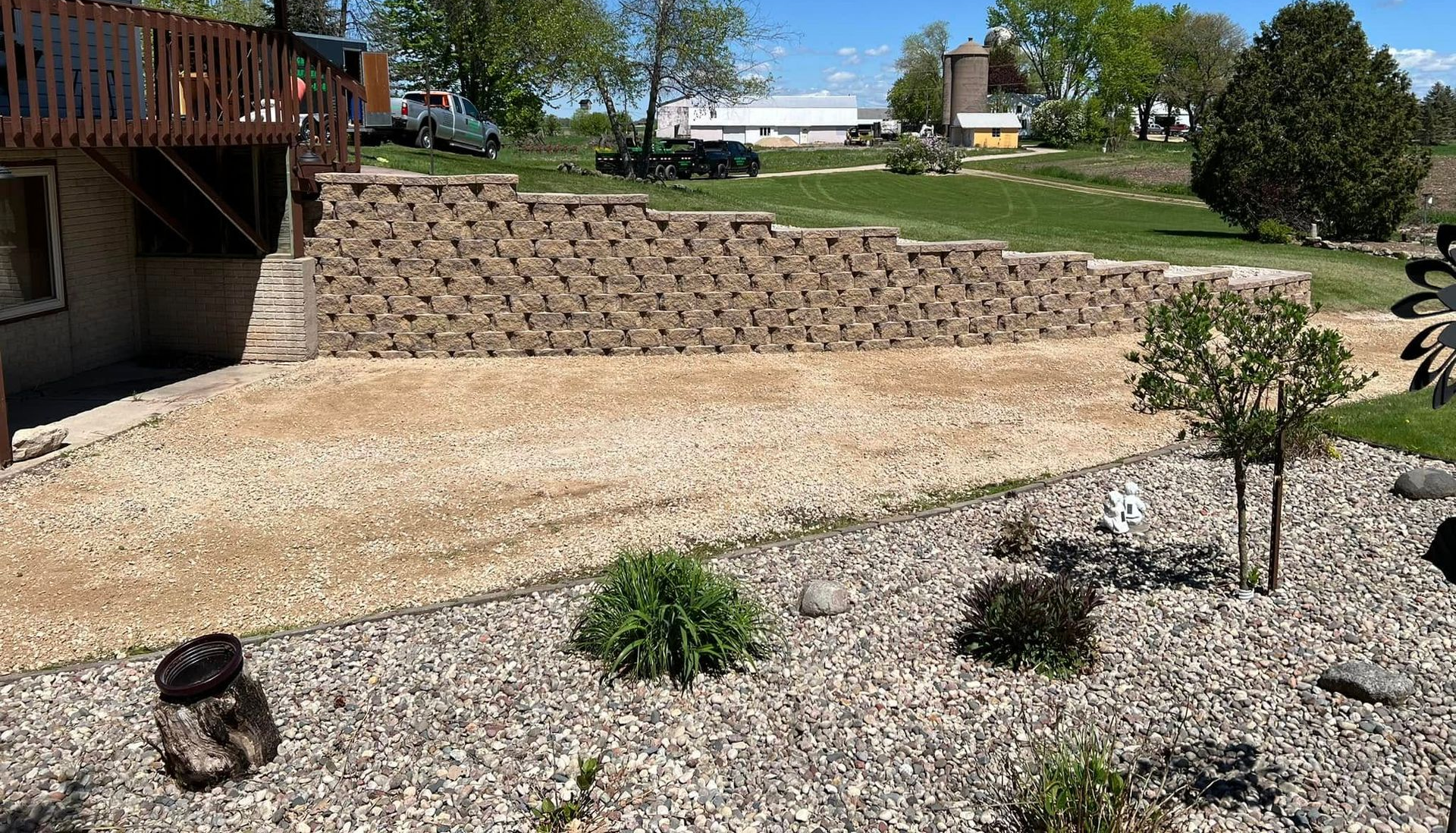 Stone patio with built-in fire pit and curved stone seating surrounded by landscaping and wooden fence. Stone patio with built-in fire pit and curved stone seating surrounded by landscaping and wooden fence.