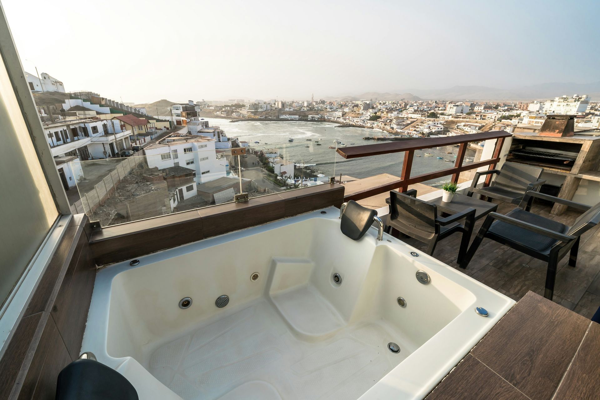 Balcony hot tub overlooking a harbor and city skyline at sunset