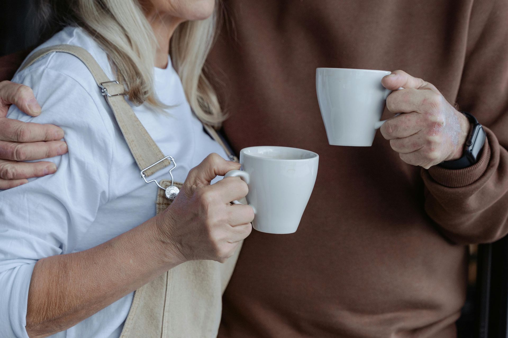En mand og en kvinde holder to kopper kaffe.