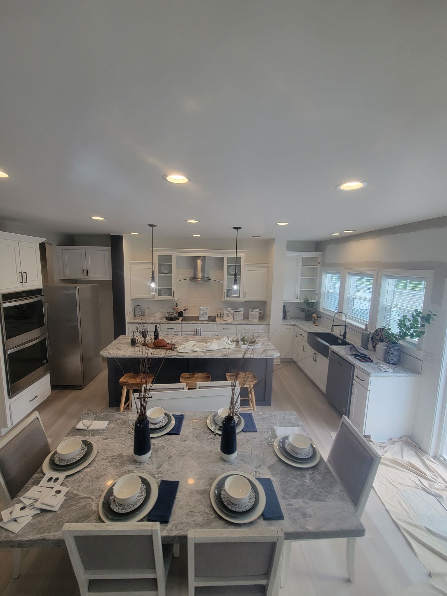 Open-concept kitchen and dining area with white cabinets, dark island, granite countertops, and dining table set for a meal.