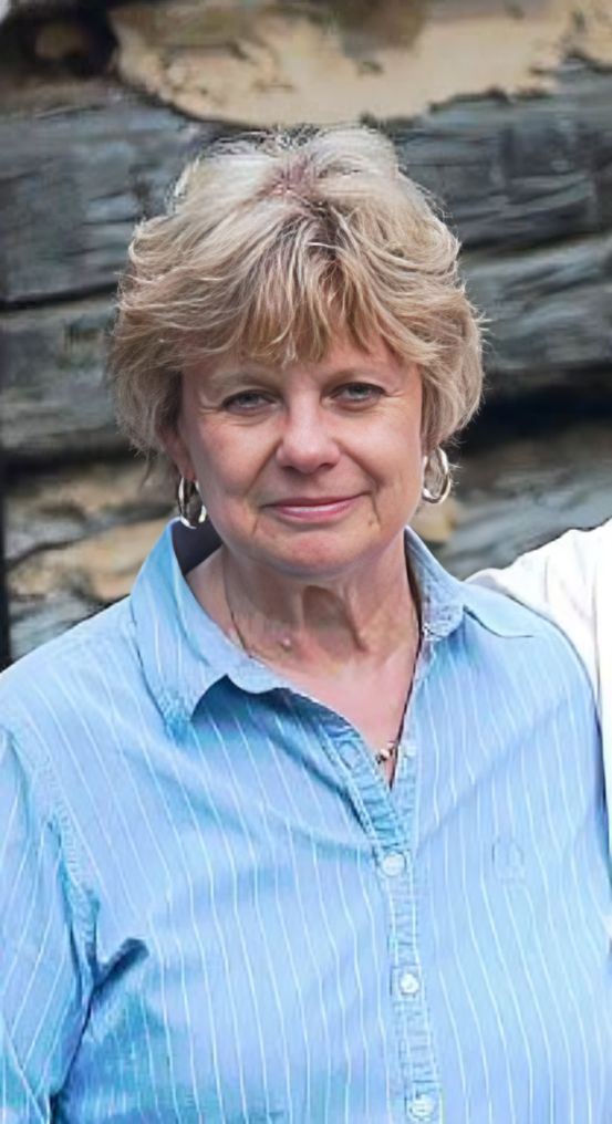 Portrait of a woman in a light blue shirt standing outdoors against a stone wall