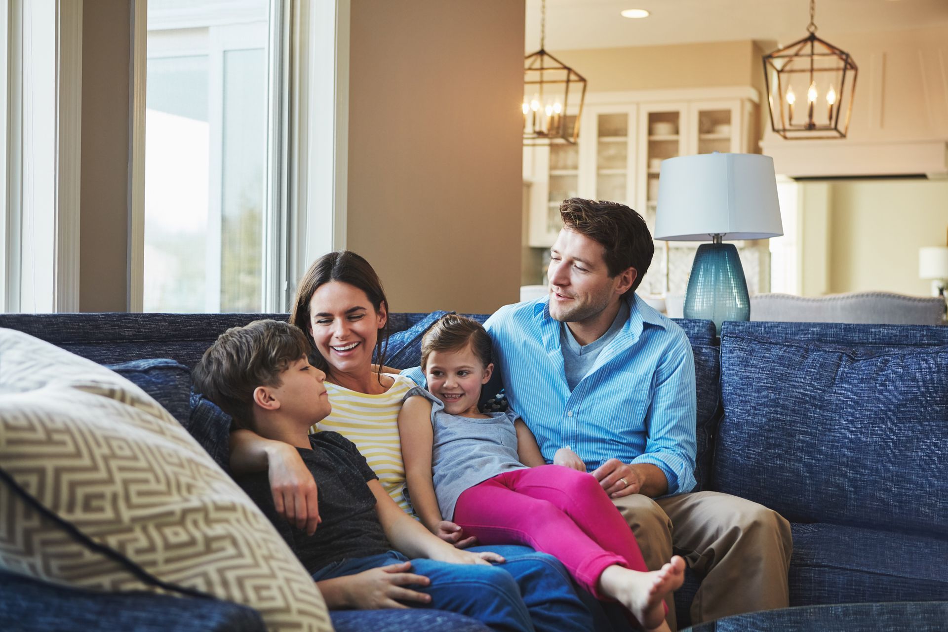 Family sitting together on a couch in a bright living room, smiling and relaxing