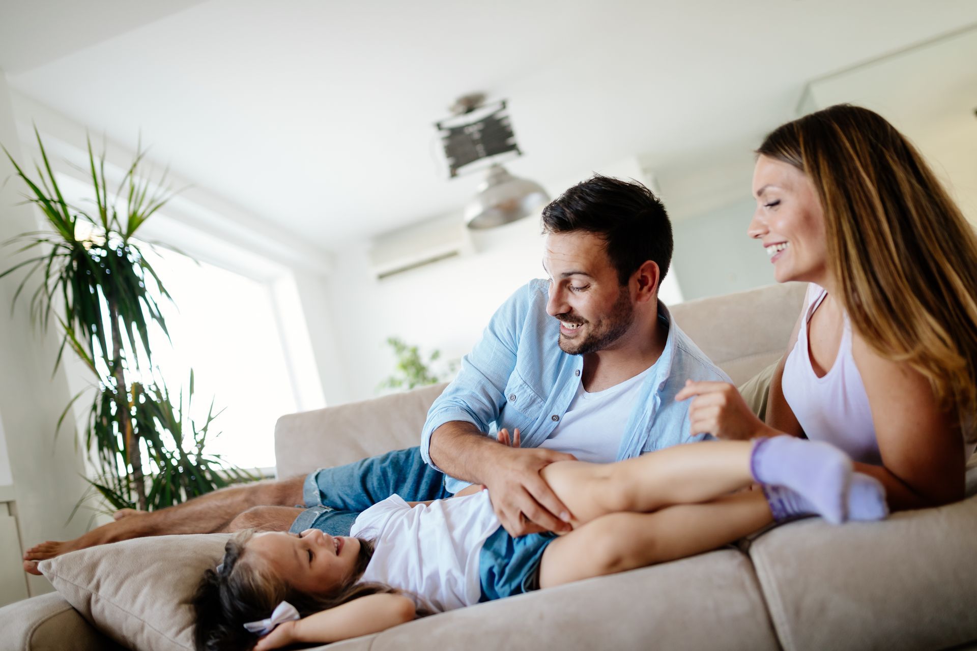 Couple relaxing on a couch with a dog in a bright living room