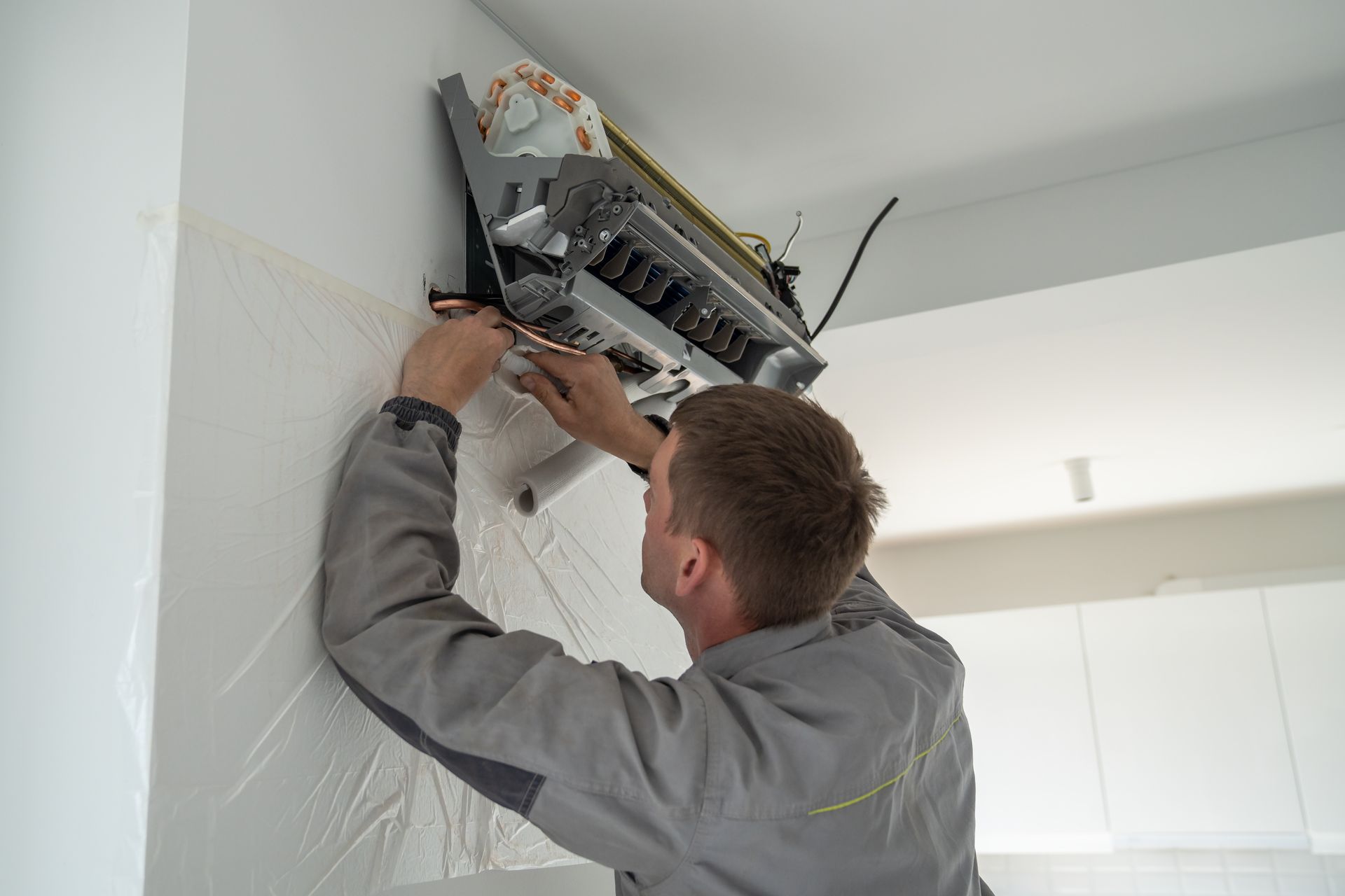 Technician repairing a wall-mounted air conditioner indoors