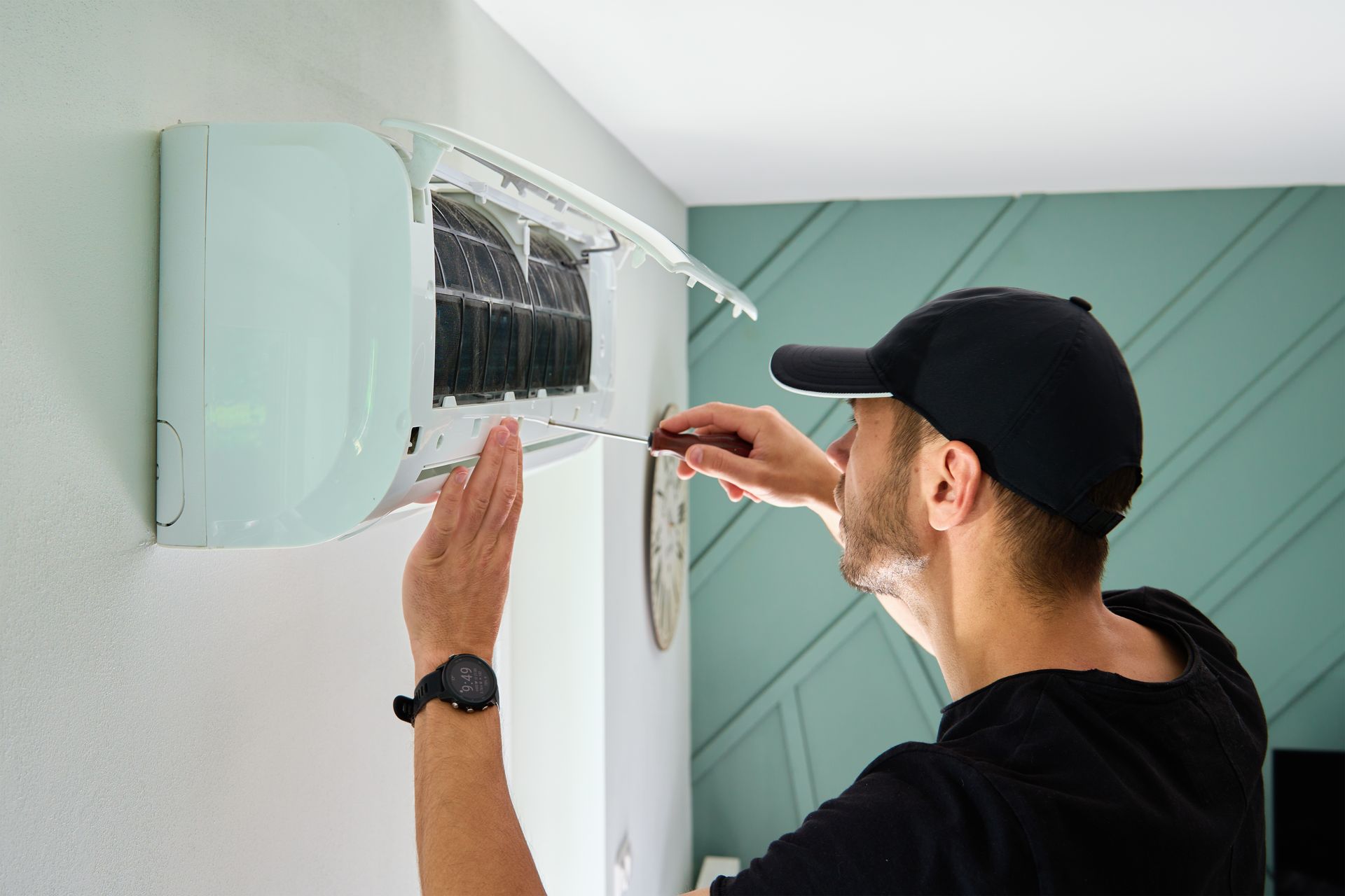 Technician installing an air conditioner on a wall with a screwdriver
