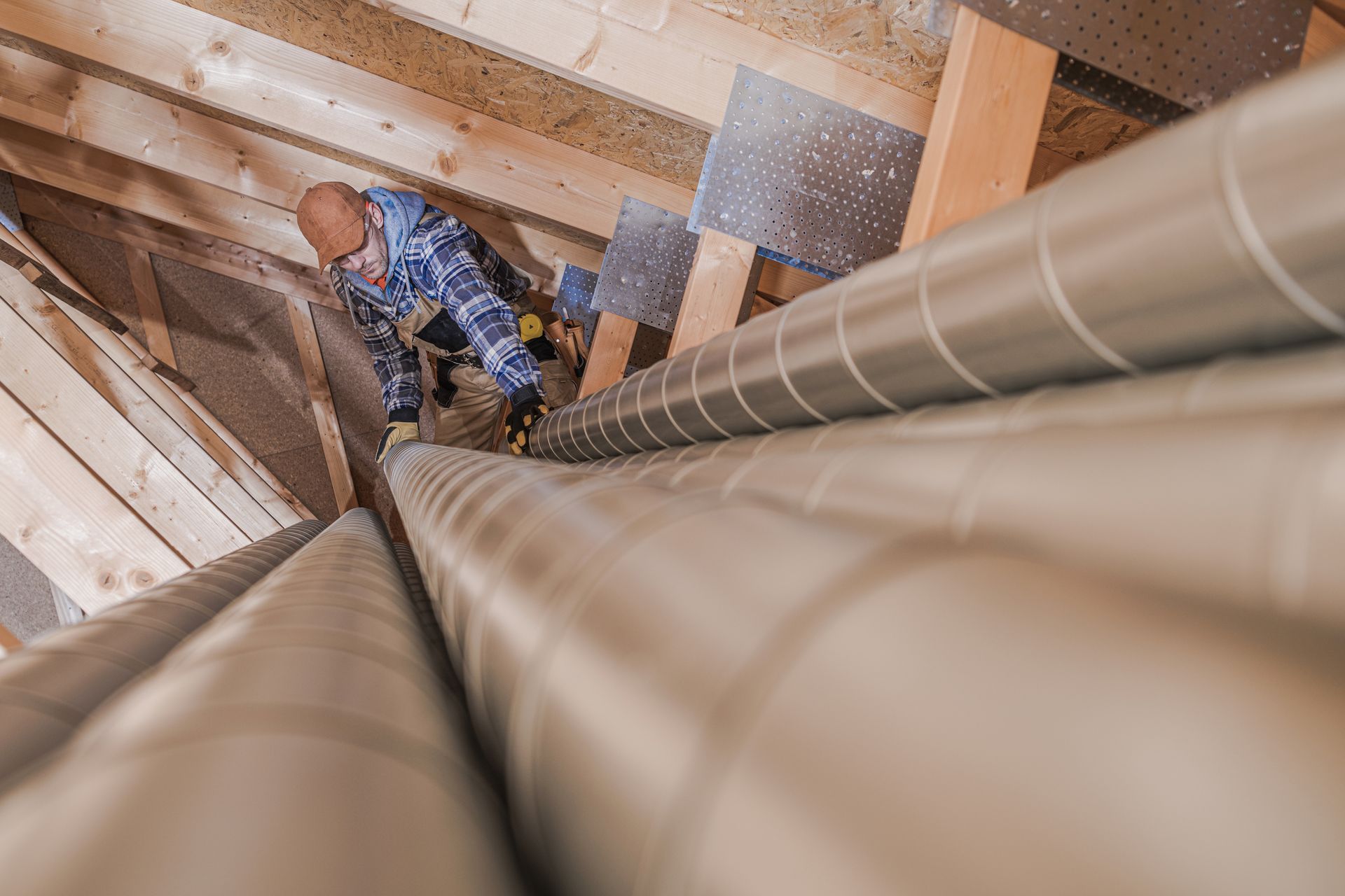 Worker descending a stairwell between large metal pipes in an unfinished building