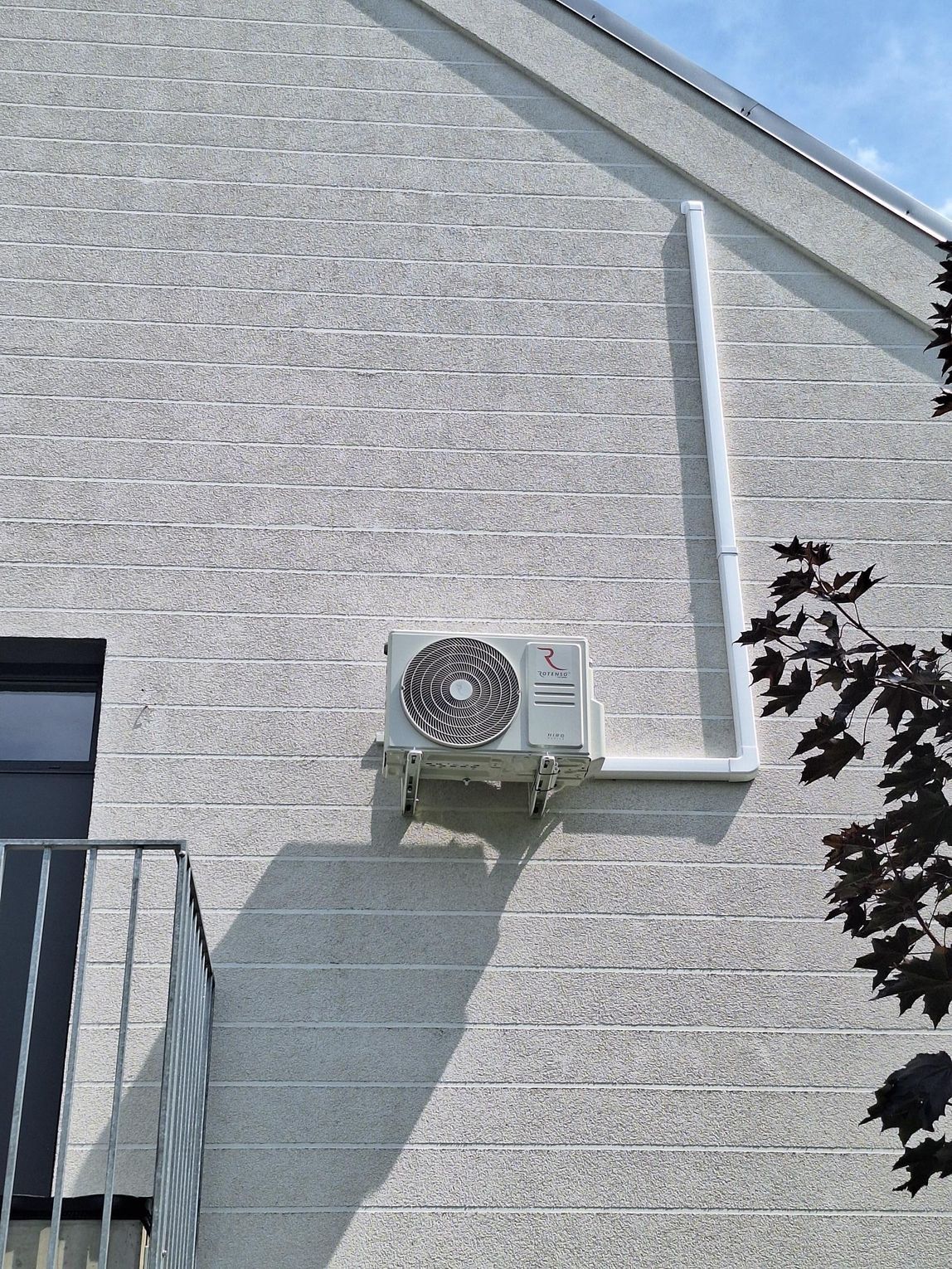 Biały klimatyzator ścienny Rotenso Revio w systemie multisplit zainstalowany w domu szeregowym.
