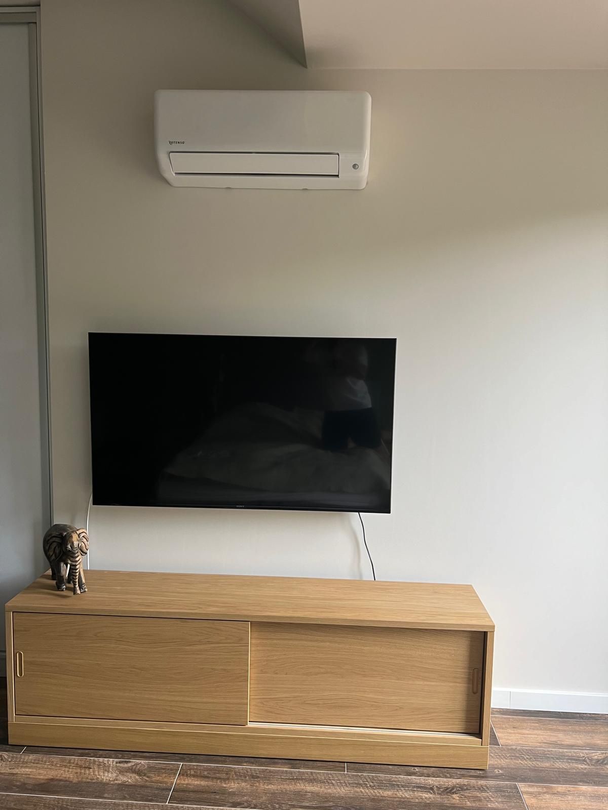 Klimatyzator ścienny Rotenso w systemie multisplit zawieszony nad telewizorem.