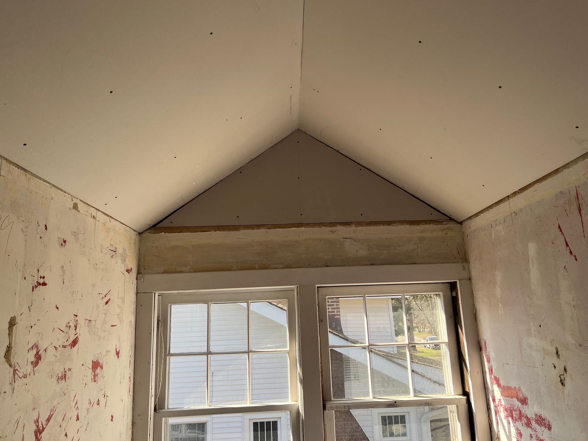 Person using a putty knife to apply spackle to a beige wall.