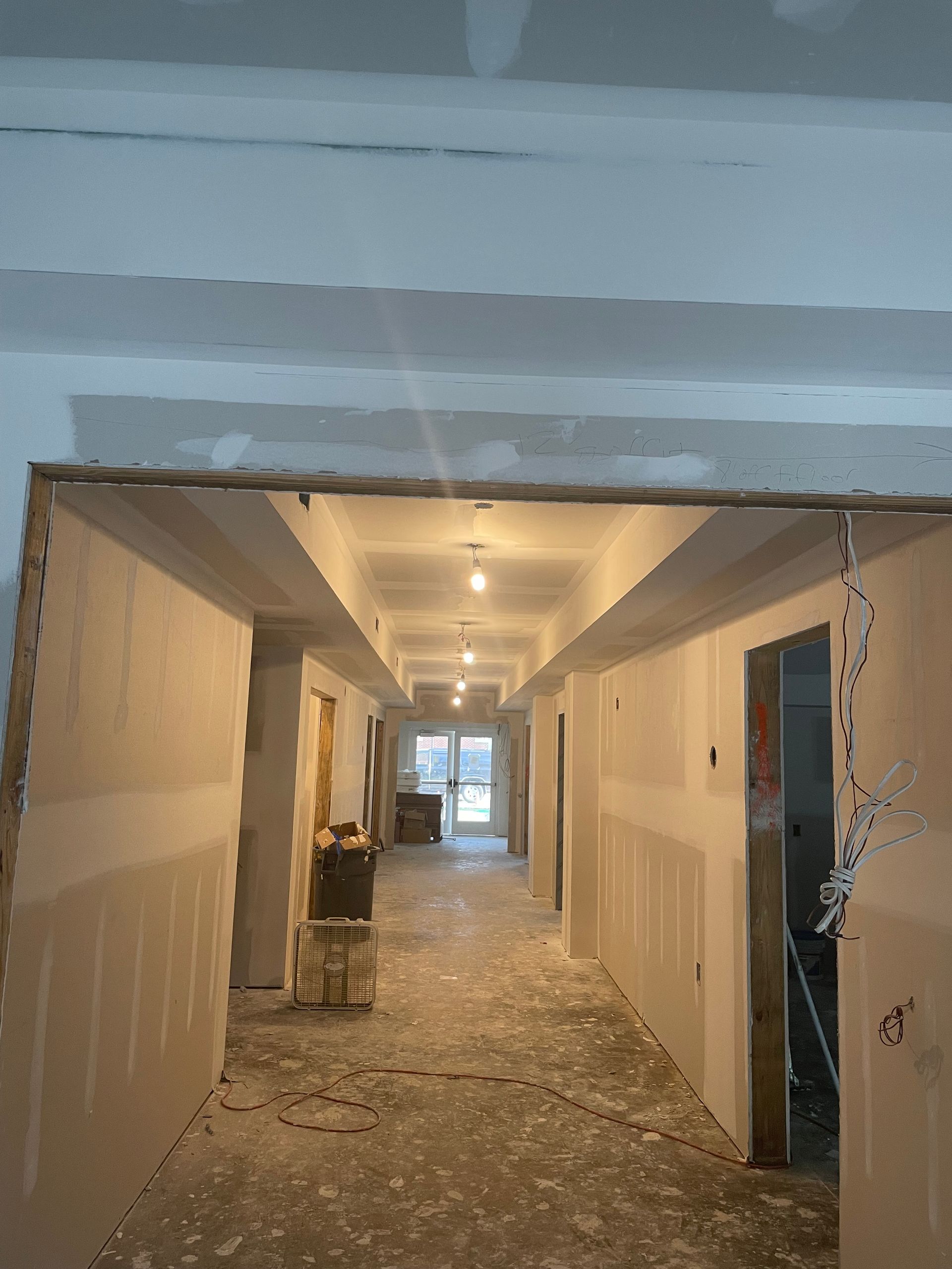 Hallway under construction with drywall and exposed framing.