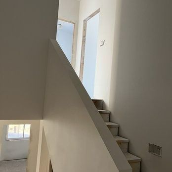Interior view: Staircase with gray steps and white walls, leading to upper level with open doorway.