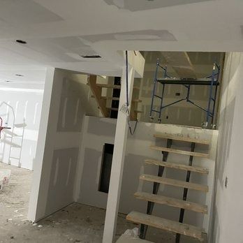 Interior construction with drywall and unfinished staircase. Scaffolding visible.