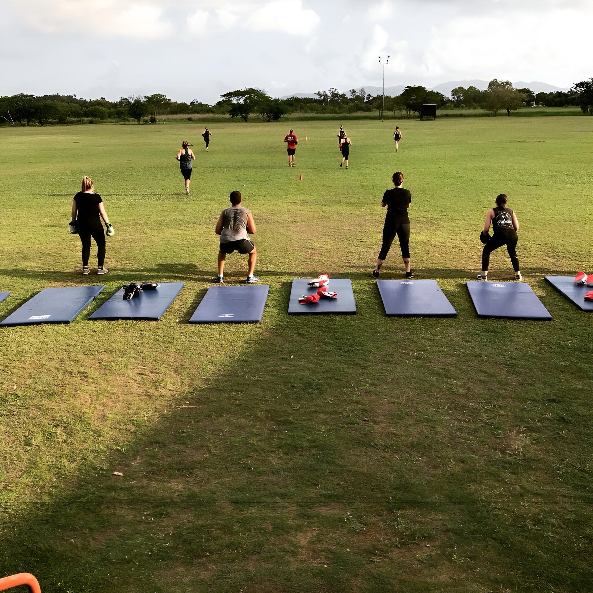 A Group of People Are Doing Exercises in a Grassy Field β Health First Townsville In Townsville, QLD