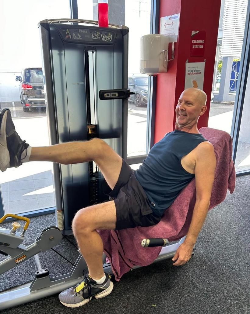 A Man is Sitting on a Machine in a Gym — Health First Townsville In Townsville, QLD