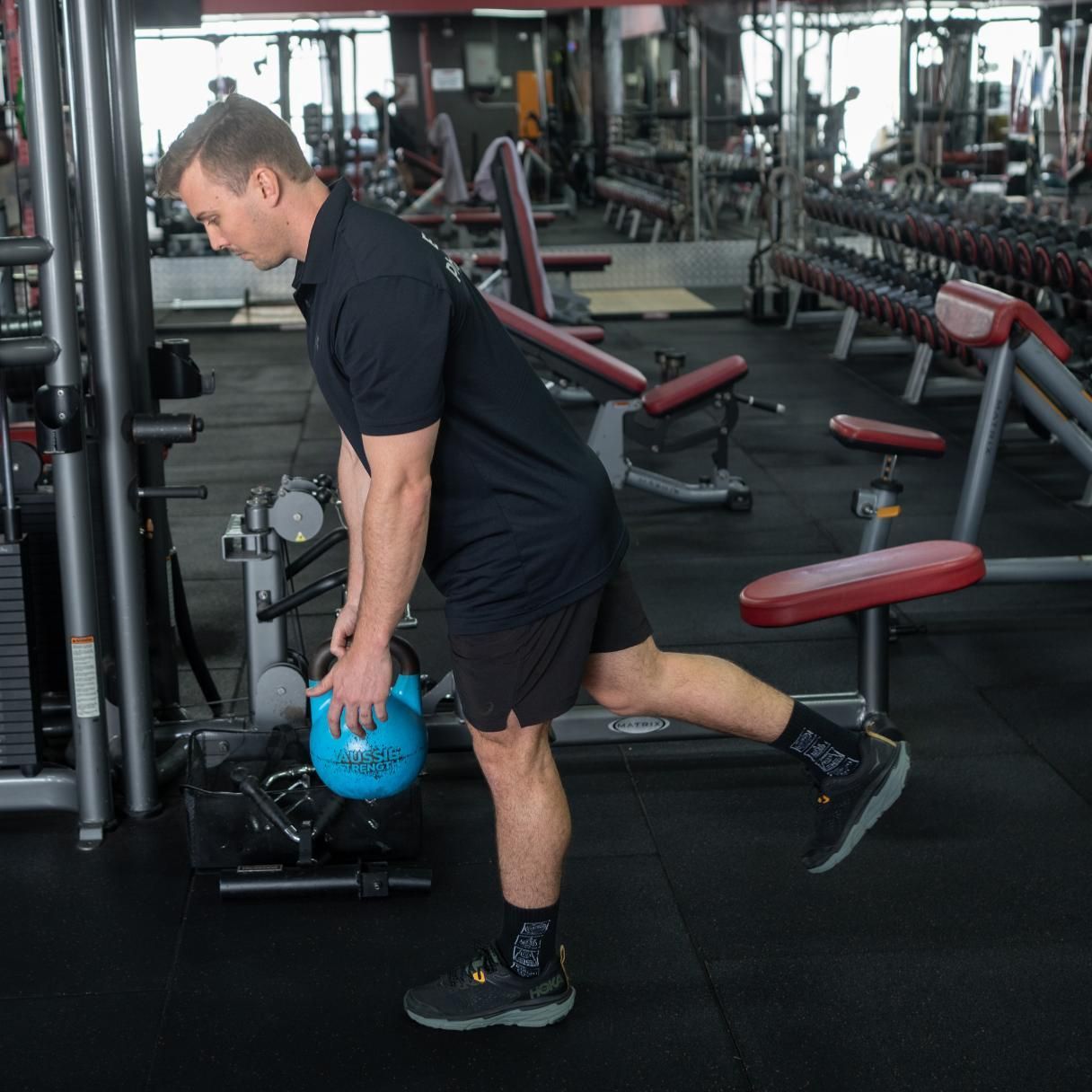 A Man is Holding a Blue Kettlebell in a Gym — Health First Townsville In Townsville, QLD