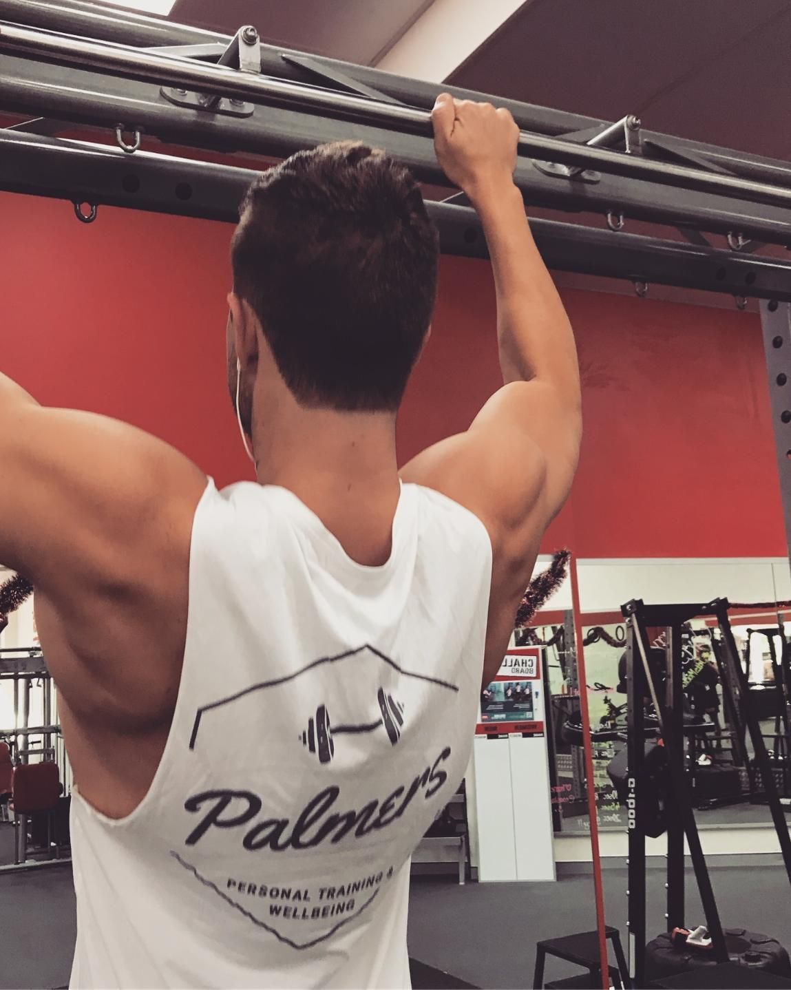 A Man Wearing a Palmer 's Tank Top is Doing Pull Ups — Health First Townsville In Townsville, QLD