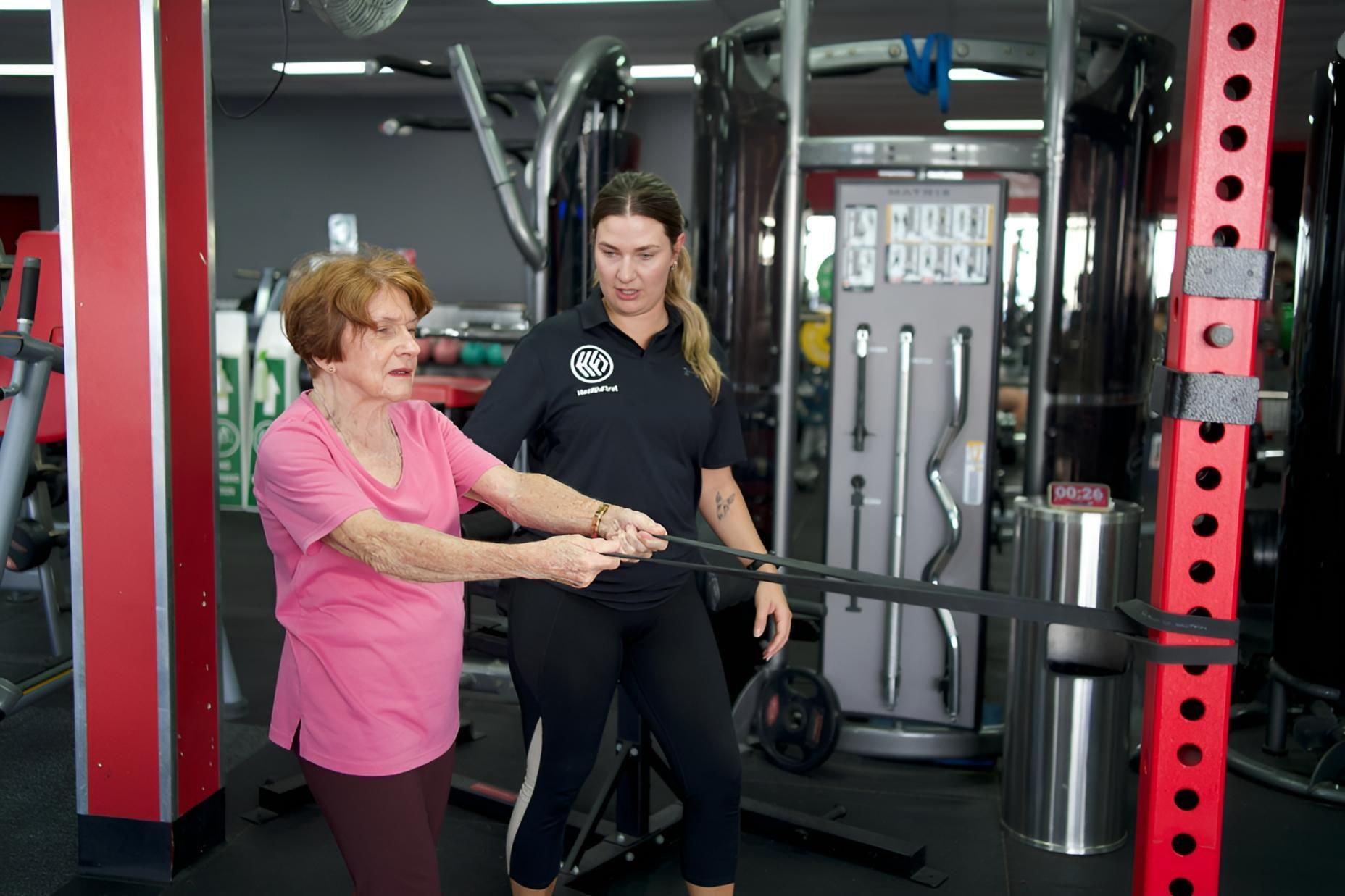 A Woman is Helping an Older Woman Do Exercises in a Gym — Health First Townsville In Townsville, QLD