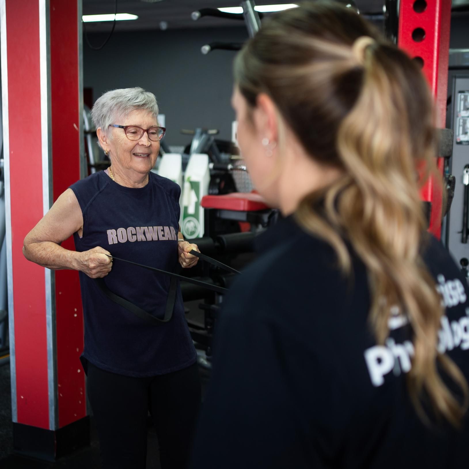 A Woman Wearing a Rocwear Shirt is Talking to Another Woman — Health First Townsville In Townsville, QLD