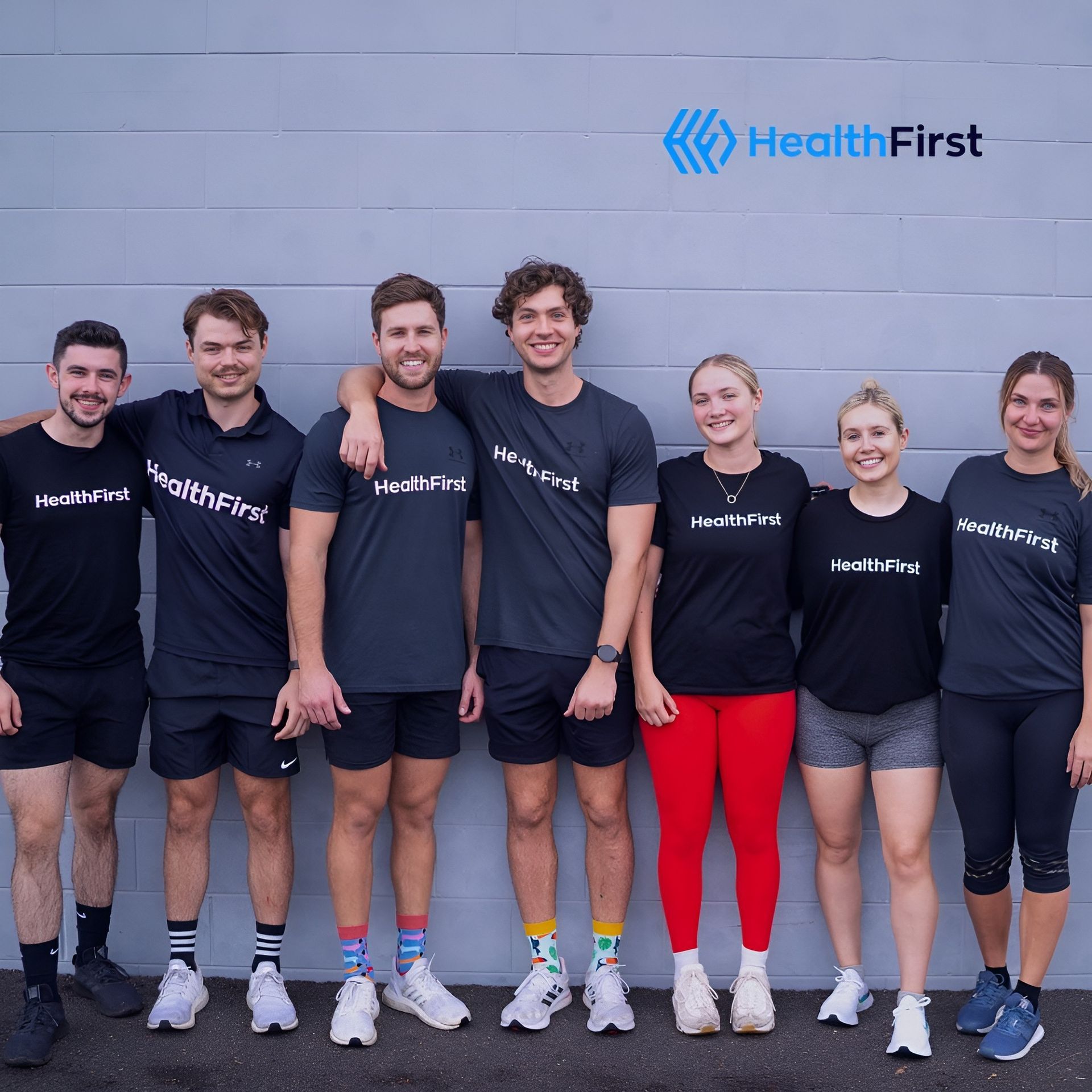 A Group of People Standing in Front of a Wall That Says Health First — Health First Townsville In Townsville, QLD