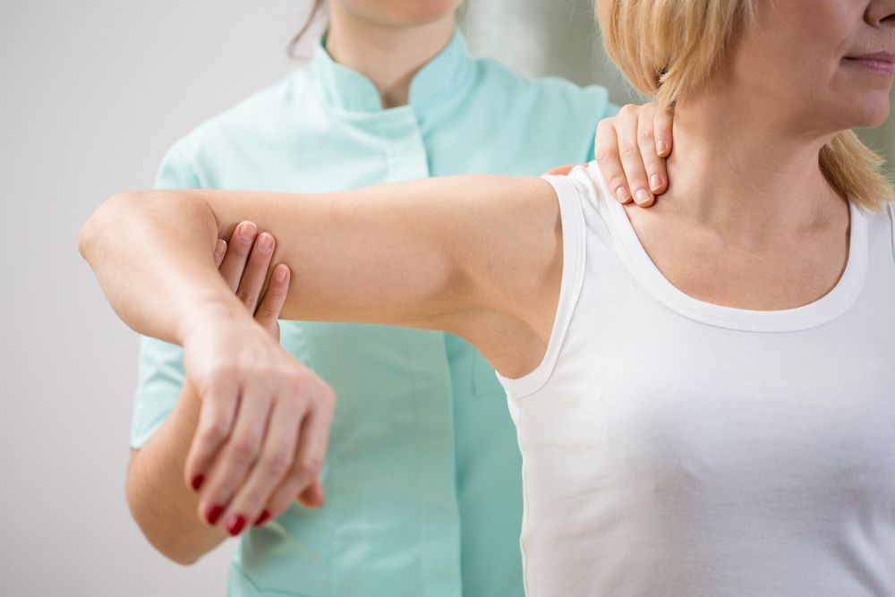 A Woman is Getting Her Shoulder Examined by a Doctor — AMC Exercise Physiology in Maitland, NSW