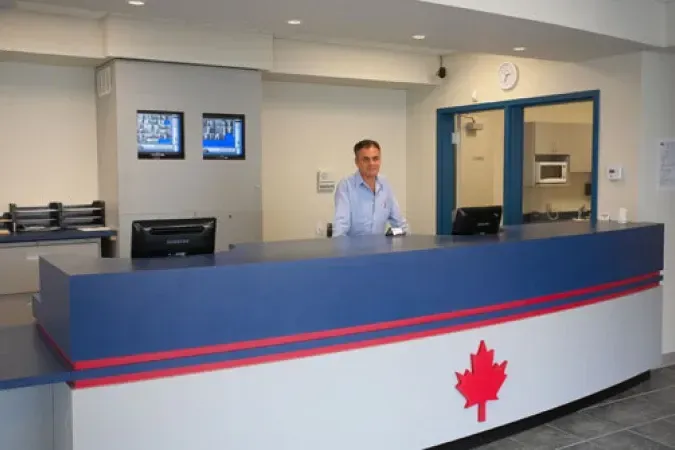 Modern reception desk with blue trim and red stripe, a man standing behind it in a lobby.