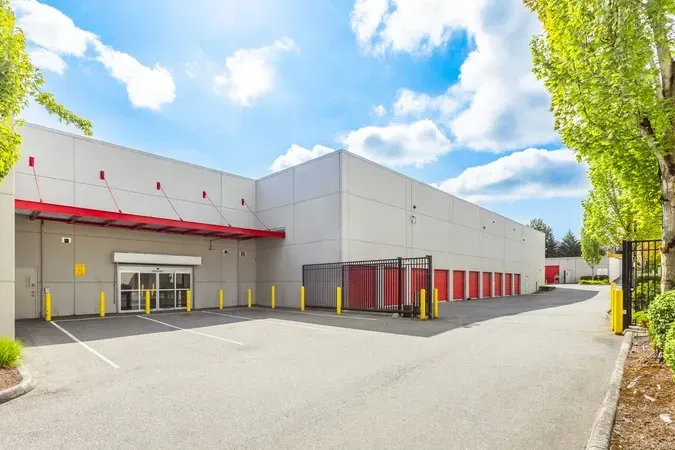 Modern commercial warehouse exterior with red accents, loading docks, and a clear paved driveway