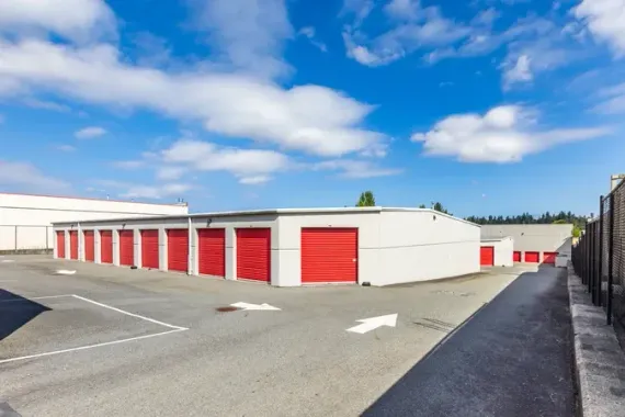 Row of red storage units in a paved lot under a blue sky