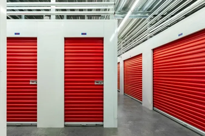 Modern commercial warehouse exterior with red accents, loading docks, and a clear paved driveway