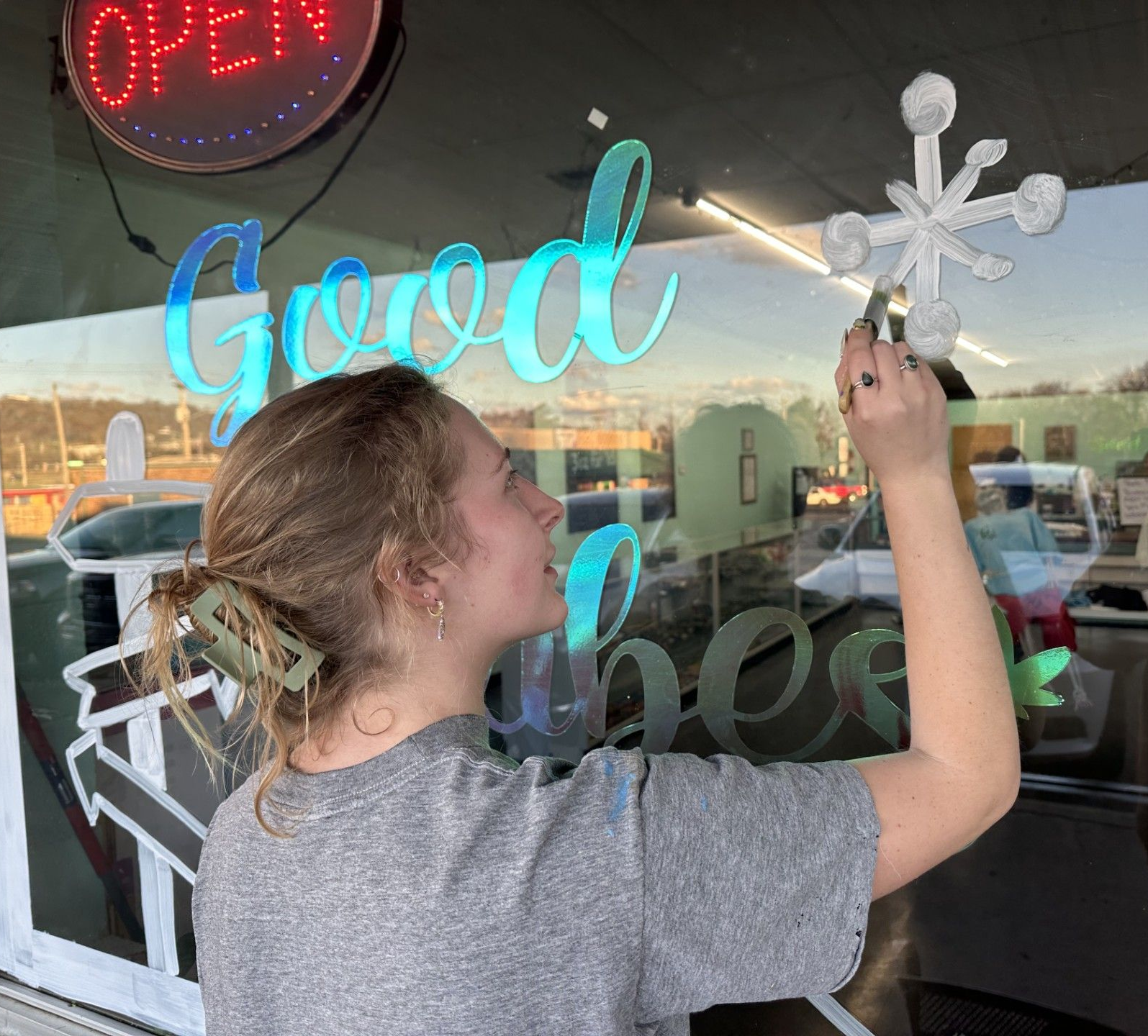 Stilwell artist Abigail Rust painting a window on a local business. 
