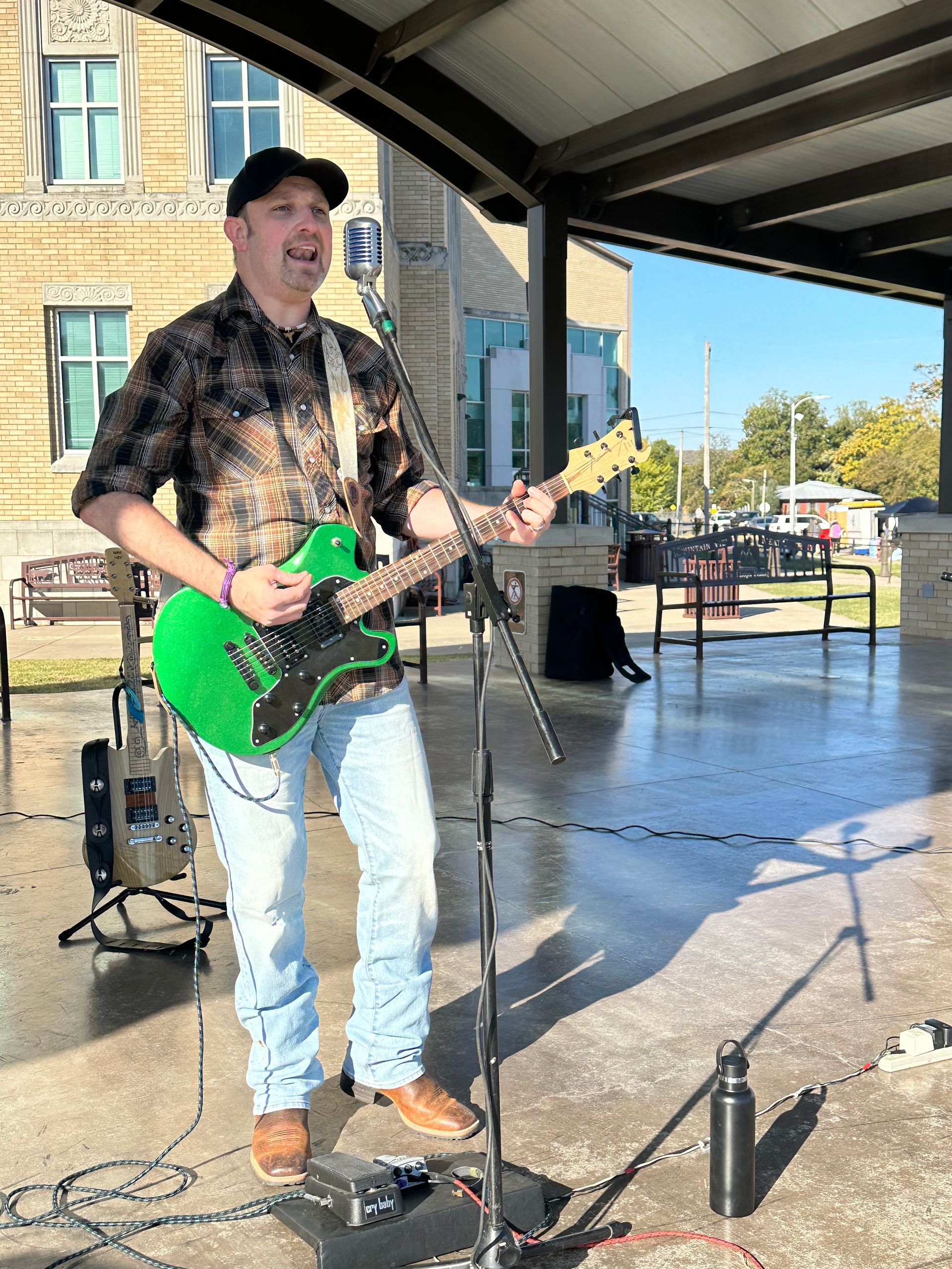 A man is playing a green guitar and singing into a microphone.