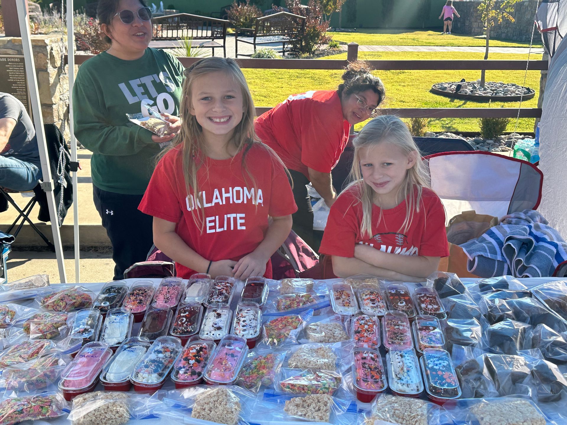 Two girls are sitting at a table with a lot of food.