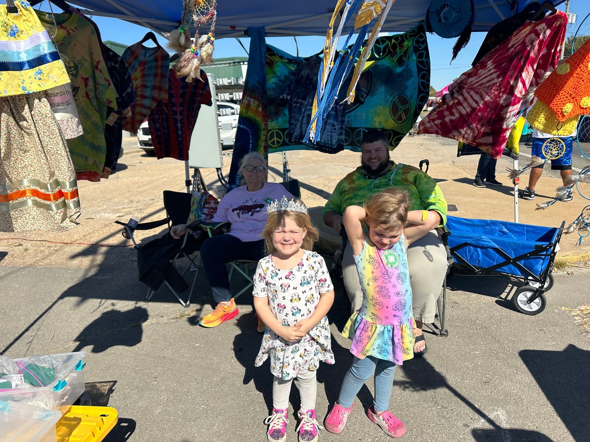 Two little girls are standing next to each other in front of a tent.