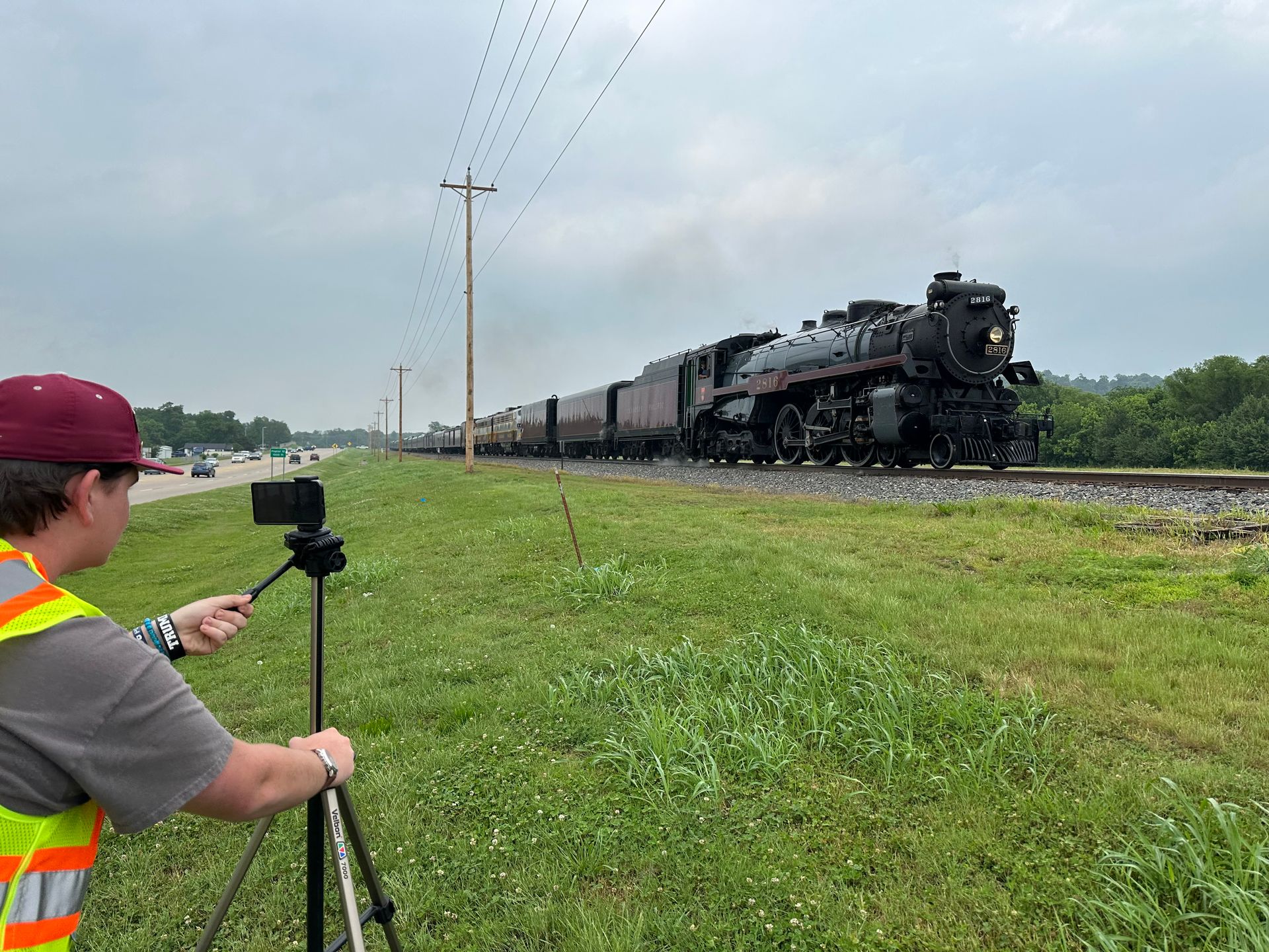 A man is taking a picture of a train on the tracks.