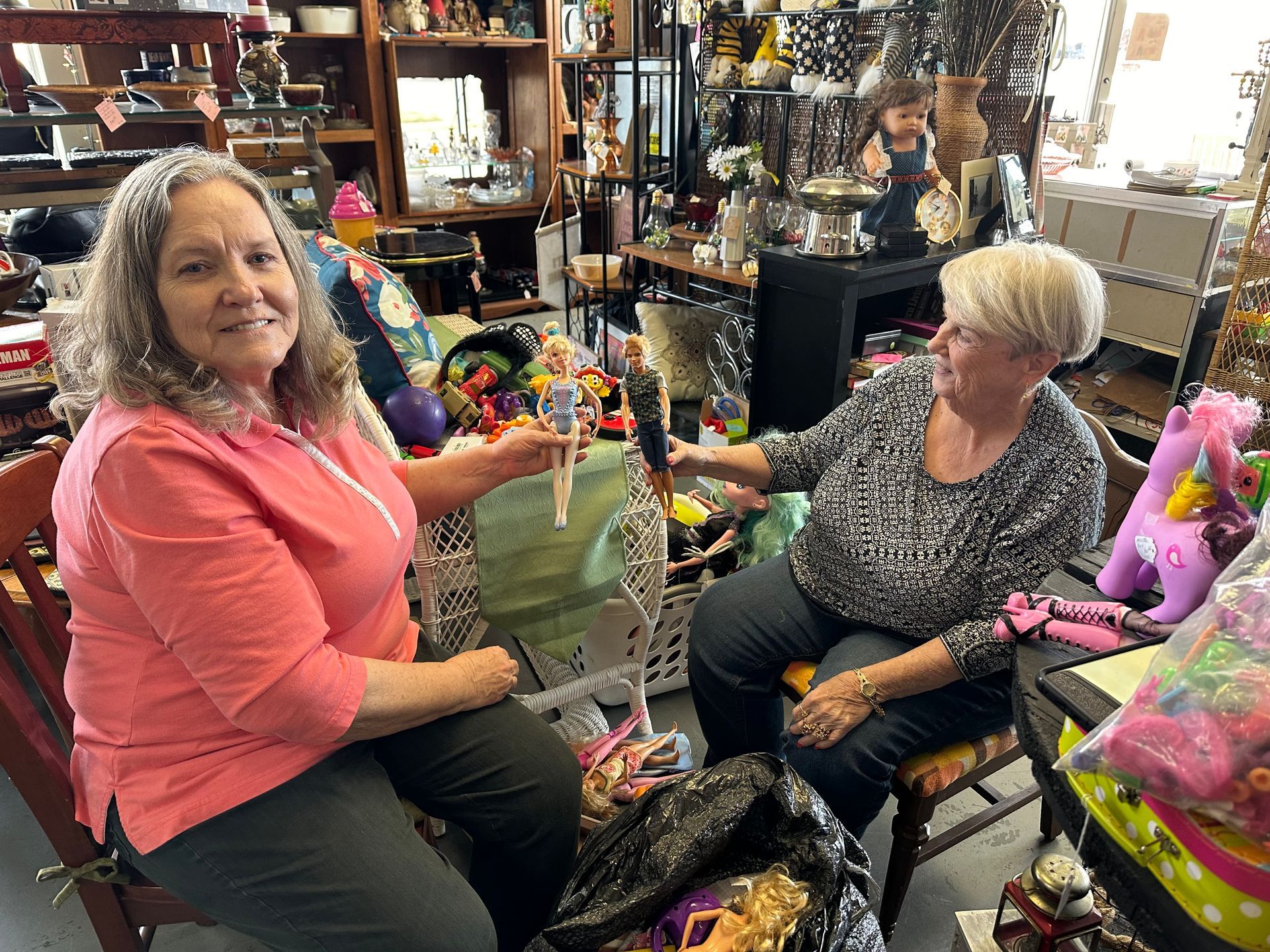 Two women are sitting in a chair in an antique store.