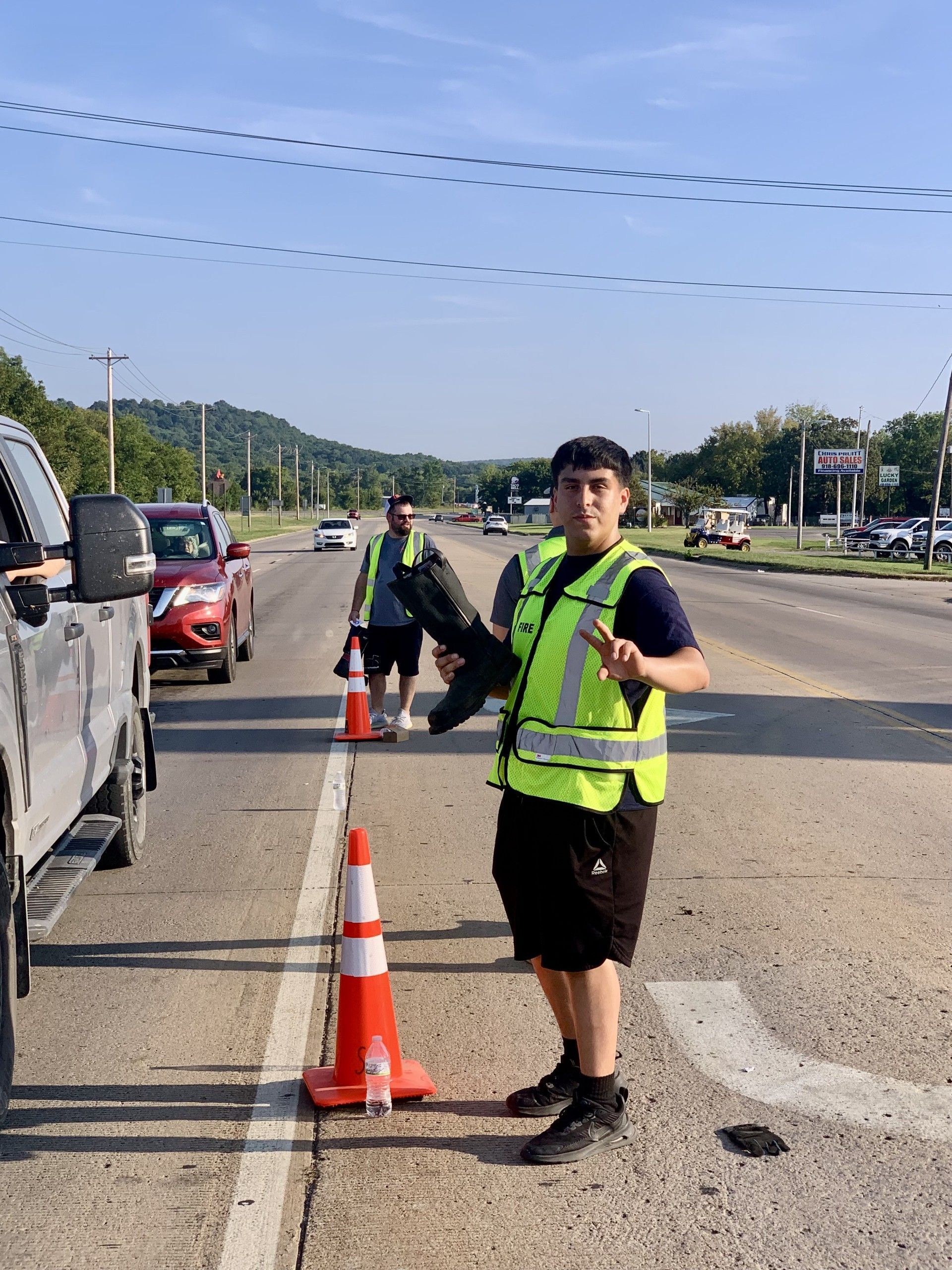 Jose Sam, front and Eric Wilson stand on the highway so people can drop cash and change in a boot for the annual Muscular Dystrophy fundraiser.