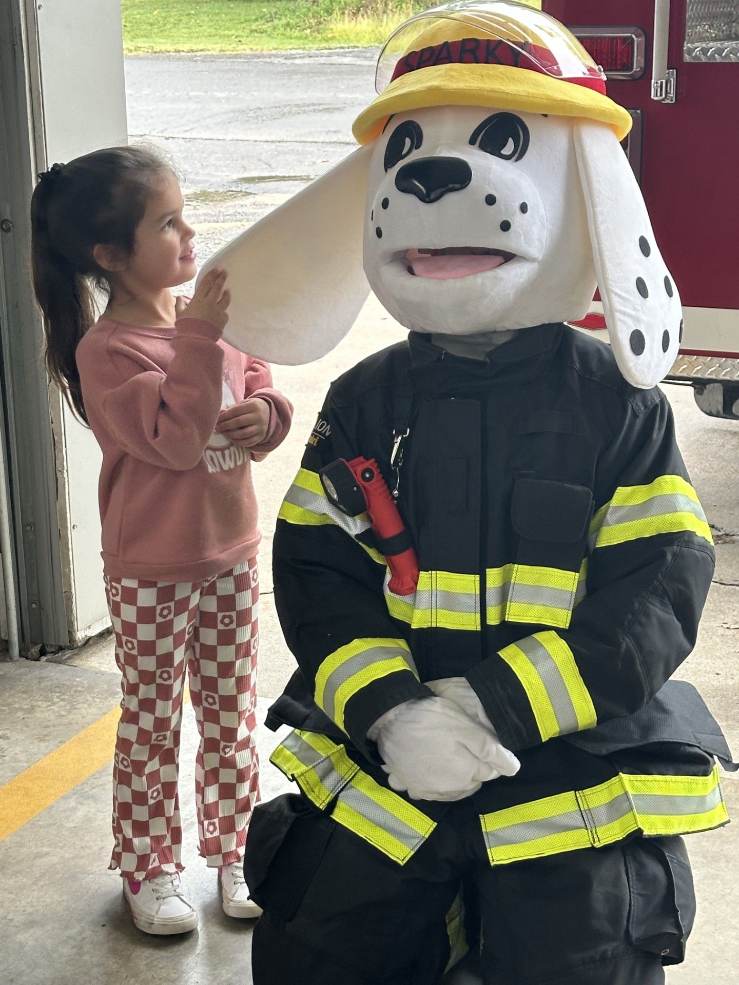 Maryetta pre-kindergarten student Mia Kester smiles at Fire Department mascot Sparky the Dog as she touches his ear.