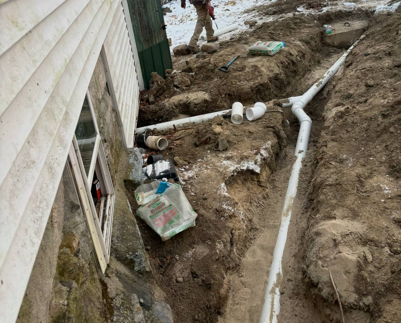 A bunch of white pipes are hanging from the ceiling in a basement.